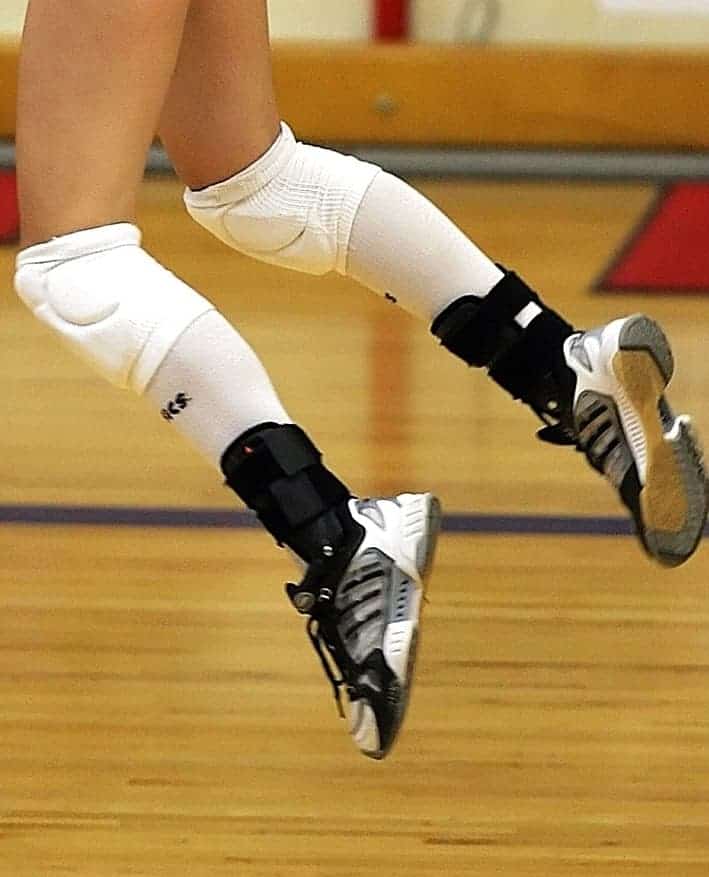 volleyball player jumping, wearing knee pads and ankle braces
