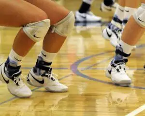 showing the legs of multiple volleyball players wearing ankle braces
