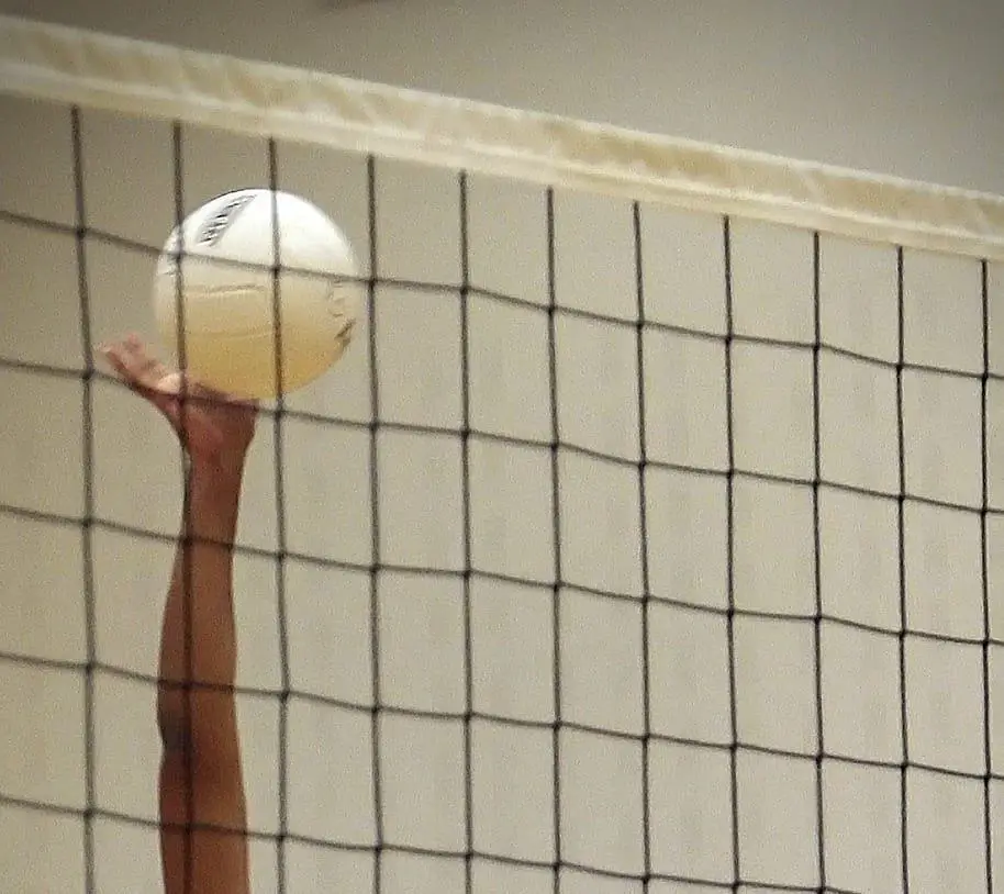 An arm reaching to hit, with the net in the foreground