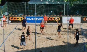 6 adults playing recreational beach volleyball