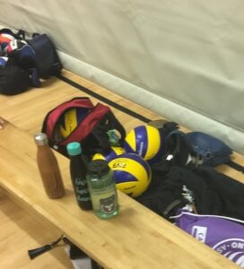 bench with volleyballs, bags, and waterbottles