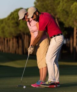 man helping woman golf