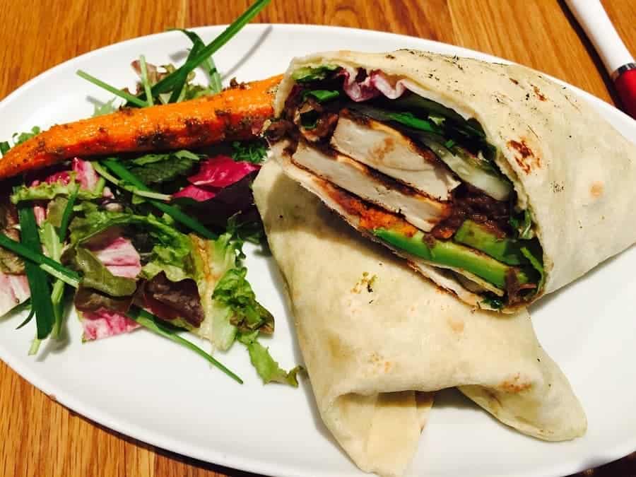 chicken wrap on a plate with a side salad