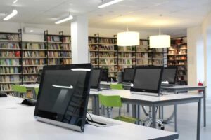 computers sitting on tables with bookshelves in the background