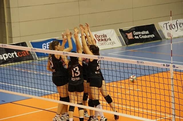 group of female volleyball players giving high fives with hands up