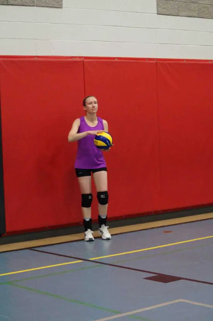 female getting ready to serve a volleyball