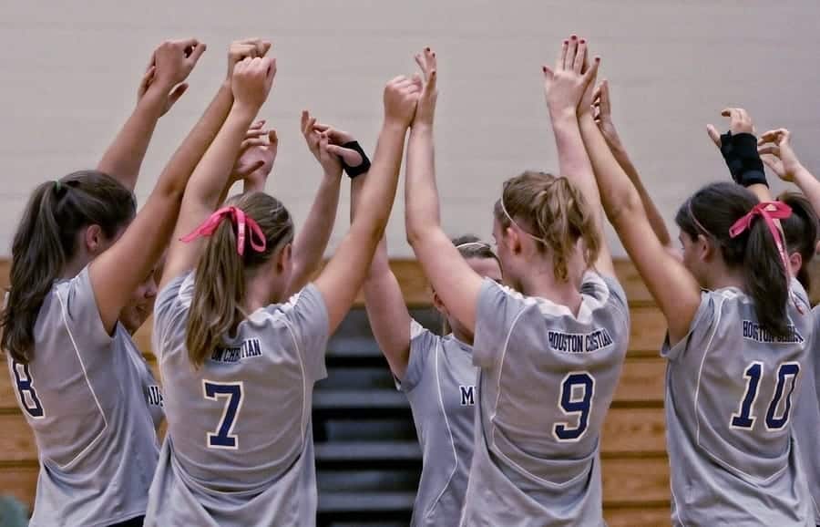 women's volleyball team doing a group high 5 during a huddle