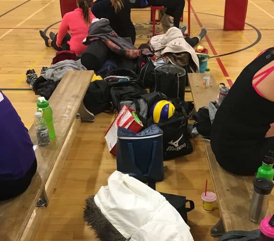 tournament benches cluttered with water bottles, bags, and volleyballs
