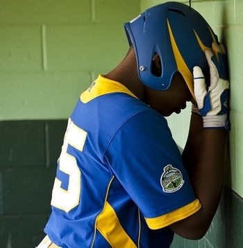 unhappy baseball player leaning against a wall