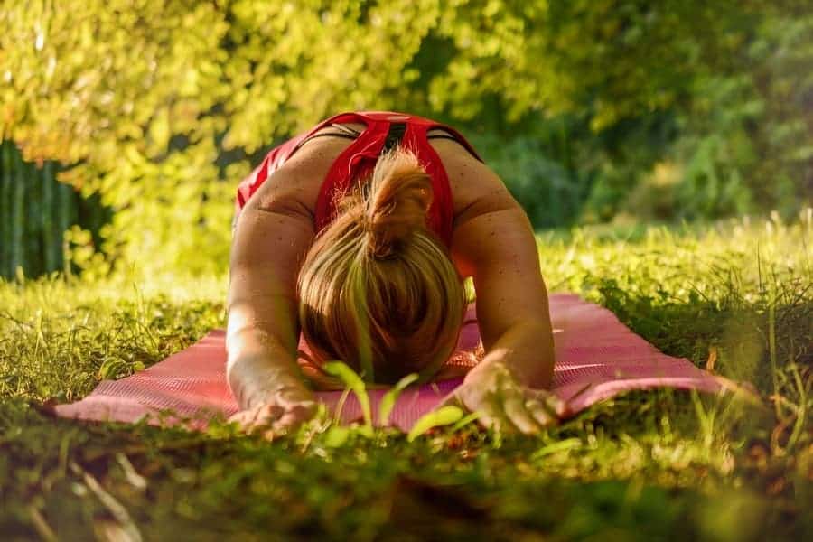 woman stretching on a yoga mat on the grass