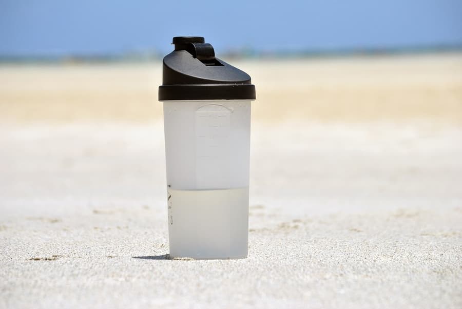 water bottle sitting on sand with beach in the background