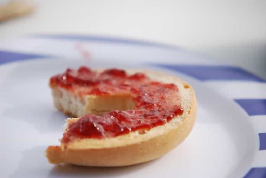 half a bagel with strawberry jam spead