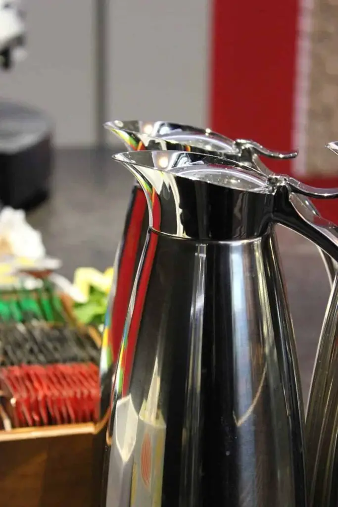 two stainless steel jugs on a buffet table