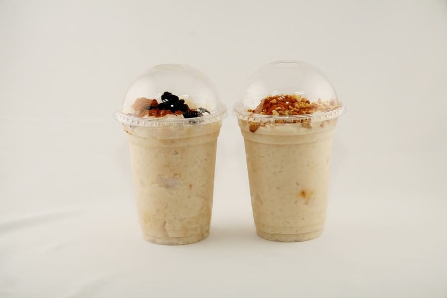 two plastic containers with yogurt, granola, and fruit