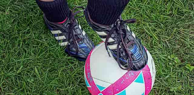 Soccer player with one foot on top of soccer ball