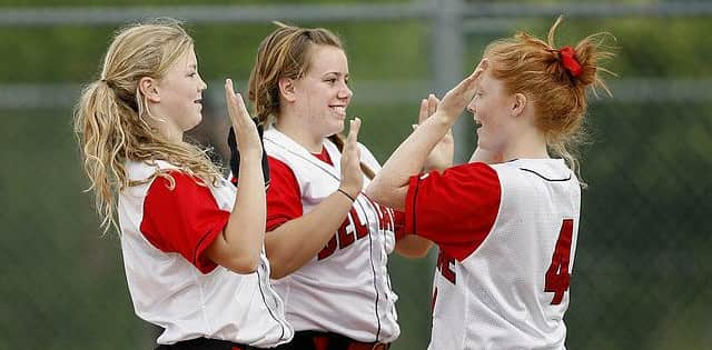 Three softball players high fiving