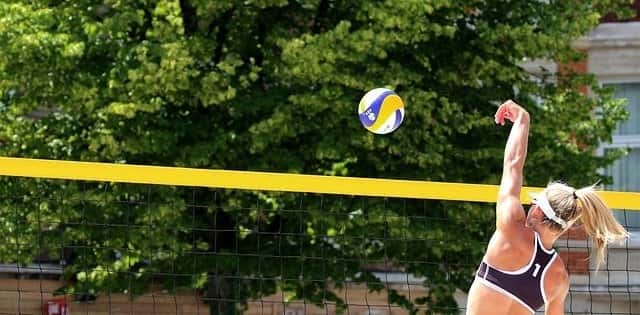 Volleyball player hitting ball over net